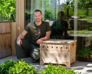 Wurmkisten-Gründer David Witzeneder neben Familienwurmkiste auf Terrasse im Sommer