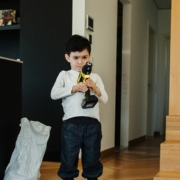 Kind mit Akkuschrauber steht im Wohnzimmer vor den Einzelteilen eines Wurmkiste Selbausets